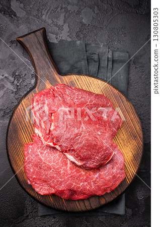 Butcher board with raw beef cheeks, uncooked meat. black background. top view 130805303