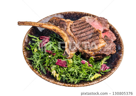 Grilled and sliced Tomahawk beef steak, marble rib eye with bone on plate with salad isolated on white background. top view 130805376