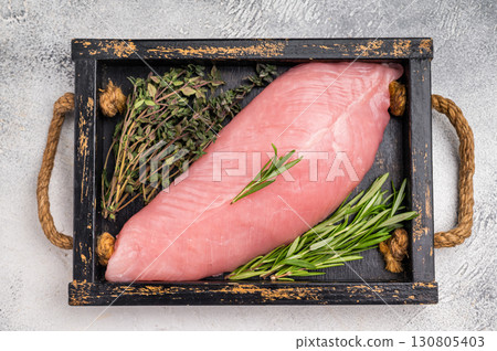 Raw poultry meat, fresh turkey breast fillet with herbs for cooking. grey background. top view 130805403