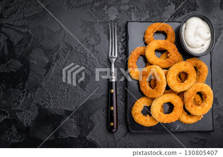 Deep fried squid rings with breading, calamari fastfood snack. black background. top view Deep fried squid rings with breading, calamari fastfood snack. black background. top view 130805407