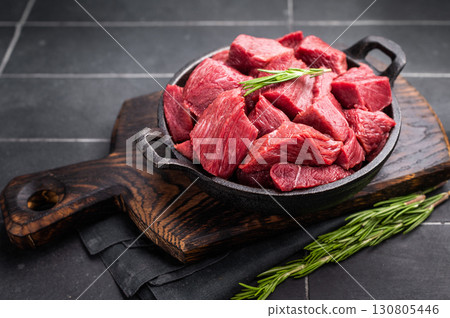 Diced Raw Ostrich meat, uncooked Game Meat in a skillet. black background. top view 130805446