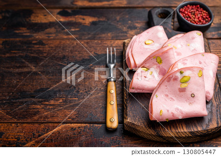 Italian Mortadella sausage slices with pistachios on wooden cutting board. wooden background. top view 130805447