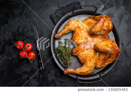 Roasted chicken Tabaka with herbs and spices, poultry meat on steel tray. black background. top view Roasted chicken Tabaka with herbs and spices, poultry meat on steel tray. black background. top view 130805465