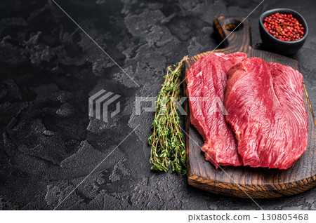 Raw Boar meat steak, uncooked Game Meat on cutting board. black background. top view Raw Boar meat steak, uncooked Game Meat on cutting board. black background. top view 130805468