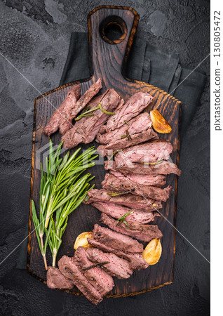 Roast Skirt Machete Steak, grilled beef meat on cutting board. black background. top view 130805472