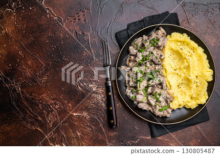 Beef stroganoff with mashed potatoes, fresh greenery and savory mushroom sauce in a plate . brown background. top view 130805487