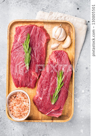 Raw Ostrich steaks, fresh Game Meat in wooden tray. grey background. top view Raw Ostrich steaks, fresh Game Meat in wooden tray. grey background. top view 130805501