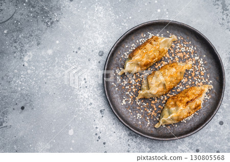 Fried Chinese Dumplings Jiaozi with meat and vegetables on plate with sauce. grey background. top view 130805568