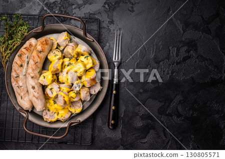 Currywurst sliced Sausages with curry sauce, wurst in steel plate. black background. top view Currywurst sliced Sausages with curry sauce, wurst in steel plate. black background. top view 130805571