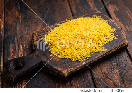 Vermicelli pasta, Raw uncooked on a wooden board. black background. top view 130805631