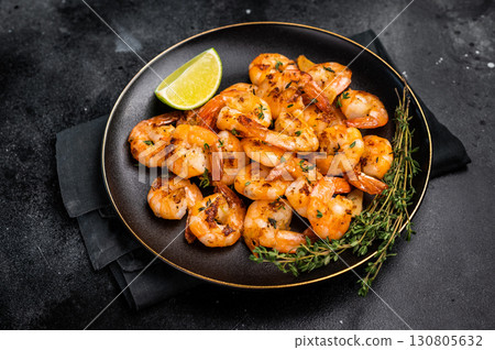 Grilled spicy Shrimps Prawns with garlic and lime in a plate. Black background. Top view Grilled spicy Shrimps Prawns with garlic and lime in a plate. Black background. Top view 130805632