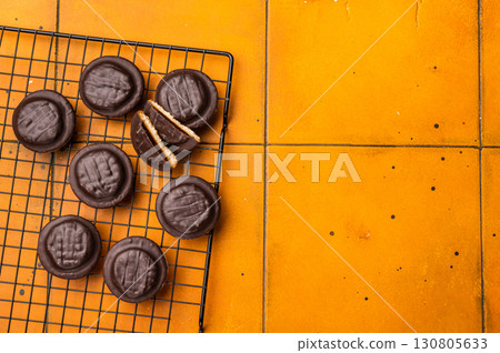 Fresh cooked Jaffa Cookies covered with chocolate and filled with jam on rack. orange background. top view Fresh cooked Jaffa Cookies covered with chocolate and filled with jam on rack. orange background. top view 130805633