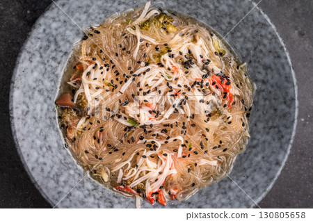 Wok with glass noodles, spicy peanut dressing, meat and vegetables. black background. top view 130805658