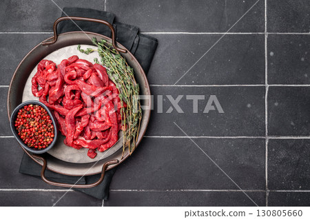 Beef sliced meat, raw veal strips for cooking beef stroganoff on a steel tray. black background. top view 130805660