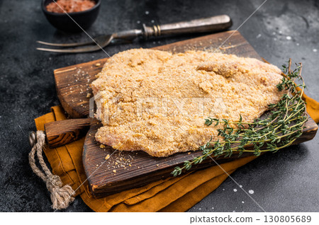 Wiener breaded raw pork Schnitzel, meat steak on a wooden board. black background. top view 130805689