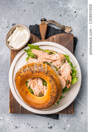 Branch with Bagel sandwich , lox, smoked salmon, lettuce and cream cheese on a plate. gray background. top view Branch with Bagel sandwich , lox, smoked salmon, lettuce and cream cheese on a plate. gray background. top view 130805808