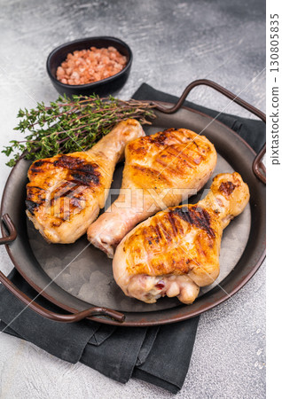 Juicy grilled chicken drumsticks, perfectly charred and bursting with flavor, ideal for a summer barbecue. grey background. top view Juicy grilled chicken drumsticks, perfectly charred and bursting with flavor, ideal for a summer barbecue. grey background. top view 130805835