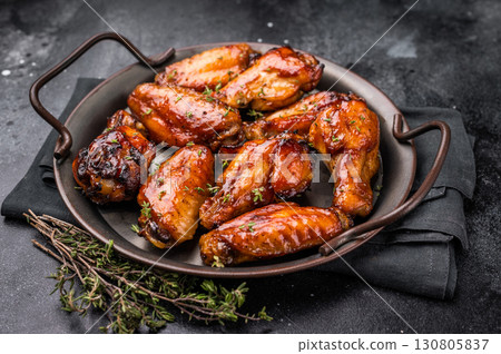 Savory grilled chicken wings smothered in tangy barbecue sauce, the ultimate treat for meat lovers and party enthusiasts. black background. top view Savory grilled chicken wings smothered in tangy barbecue sauce, the ultimate treat for meat lovers and party enthusiasts. black background. top view 130805837