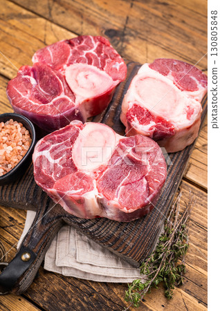 Fresh raw ossobuco, osso buco meat, showcasing tender veal shank with rich marrow, perfect for gourmet Italian dishes. wooden background. top view 130805848