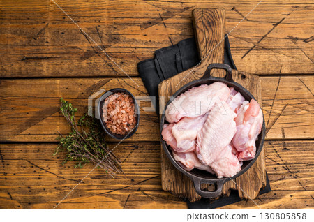Juicy uncooked chicken wings, a versatile ingredient perfect for frying, baking, or grilling to perfection. wooden background. top view Juicy uncooked chicken wings, a versatile ingredient perfect for frying, baking, or grilling to perfection. wooden background. top view 130805858