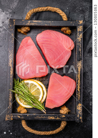 Freshly sliced raw tuna loin fillet, packed with flavor and nutrients, waiting to be transformed into exquisite seafood dishes. black background. top view 130805863