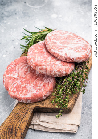 Frozen raw Hamburger beef Patty, uncooked mincemeat. grey background. top view 130805958
