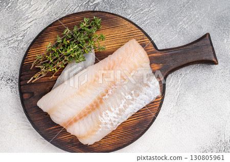 Tender Pacific cod loin, raw fish fillet featuring a light hue and flaky texture, perfect for pan-searing or steaming. grey background. top view Tender Pacific cod loin, raw fish fillet featuring a light hue and flaky texture, perfect for pan-searing or steaming. grey background. top view 130805961