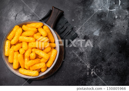 Deliciously addictive cheese flavored corn puffs, beautifully arranged on a plate. black background. top view 130805966