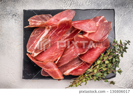 Sliced Speck bacon, Italian cured meat. grey background. top view Sliced Speck bacon, Italian cured meat. grey background. top view 130806017