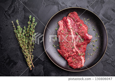 Raw hanger tender beef steak, skirt steak on plate with herbs and spices. black background. top view Raw hanger tender beef steak, skirt steak on plate with herbs and spices. black background. top view 130806047