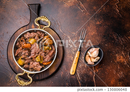 Slow cooked Beef Cheek, Braised meat with vegetables in a skillet. brown background. top view Slow cooked Beef Cheek, Braised meat with vegetables in a skillet. brown background. top view 130806048