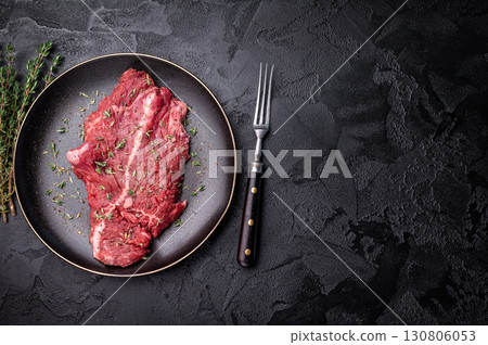 Raw hanger tender beef steak, skirt steak on plate with herbs and spices. black background. top view 130806053
