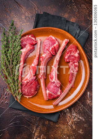 Uncooked lamb chops, fresh mutton meat steaks on a plate. brown background. top view Uncooked lamb chops, fresh mutton meat steaks on a plate. brown background. top view 130806065