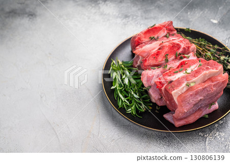 Raw Beef Kalbi Short Ribs, fresh meat with bone on plate with thyme. grey background. top view 130806139