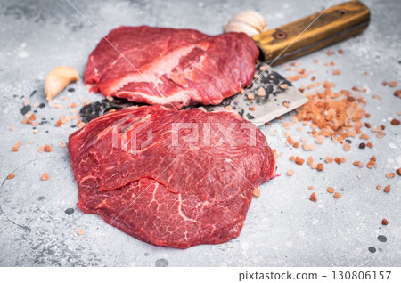 Raw beef cheeks on butcher meat cleaver. grey background. top view 130806157