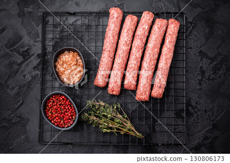 Uncooked Raw Cevapcici Sausage, fresh Cevapi from mince beef and pork meat on a rack. black background. top view Uncooked Raw Cevapcici Sausage, fresh Cevapi from mince beef and pork meat on a rack. black background. top view 130806173