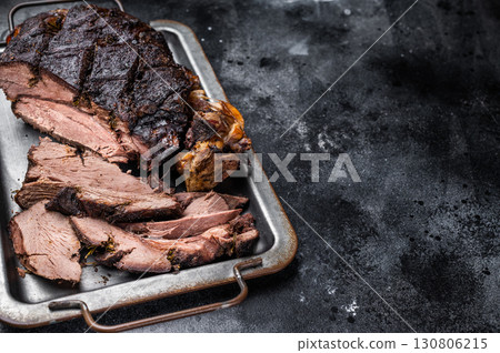 Roast Venison leg, baked meat of roe deer with bone on a tray with herbs. black background. top view 130806215