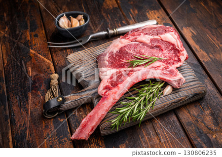 Raw Tomahawk beef steak, fresh black angus ribeye with bone on wooden board. wooden background. top view Raw Tomahawk beef steak, fresh black angus ribeye with bone on wooden board. wooden background. top view 130806235