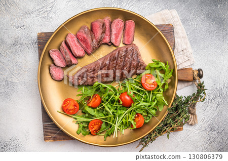 Grill Goat steak, roasted tenderloin fillet meat with salad. grey background. top view 130806379