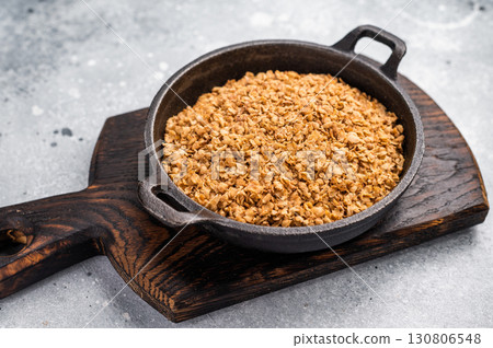 Raw buckwheat flakes in a skillet. grey background. top view Raw buckwheat flakes in a skillet. grey background. top view 130806548