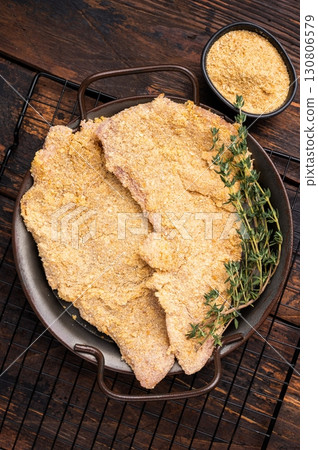 Viennese breaded raw Schnitzel steak on a tray. wooden background. top view Viennese breaded raw Schnitzel steak on a tray. wooden background. top view 130806579