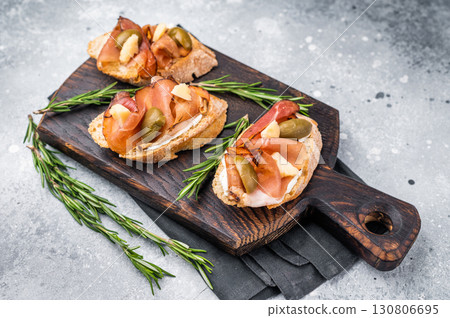 Tapa with Jamon cured ham, parmesan cheese and olives. grey background. top view Tapa with Jamon cured ham, parmesan cheese and olives. grey background. top view 130806695