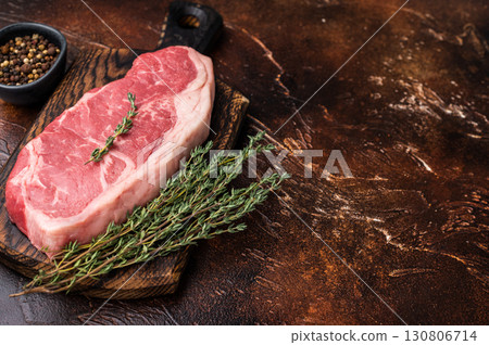 Raw New York strip beef steak, also named Striploin steak on a wooden board. brown background. top view Raw New York strip beef steak, also named Striploin steak on a wooden board. brown background. top view 130806714