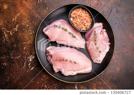 Raw Chicken thigh fillet meat, Skinless boneless poultry meat on a plate. brown background. top view Raw Chicken thigh fillet meat, Skinless boneless poultry meat on a plate. brown background. top view 130806727
