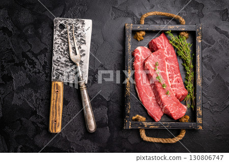Raw skirt or machete Steak, beef meat in wooden tray with herbs. black background. top view 130806747