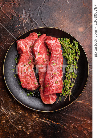 Tri tip steaks, Raw marbled beef meat on plate with herbs. brown background. top view 130806767