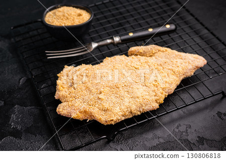 Raw breaded pork Schnitzel steak on a rack. black background. top view 130806818