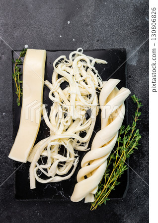 Assortiment of Traditional Caucasian Chechil white cheese on black board, top view. Assortiment of Traditional Caucasian Chechil white cheese on black board, top view. 130806826