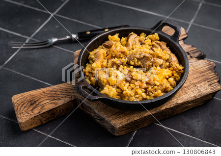 Pilaf with beef and lamb meat, vegetables in a skillet. black background. top view Pilaf with beef and lamb meat, vegetables in a skillet. black background. top view 130806843