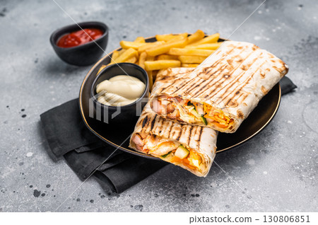 Chicken Fajita wrap sandwich with fresh salad and french fry on a plate. gray background. top view 130806851